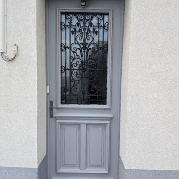 Porte d'entrée en bois sur mesure installée par Menuiserie EGI à Rouen avec finition RAL 7004 et grille restaurée.