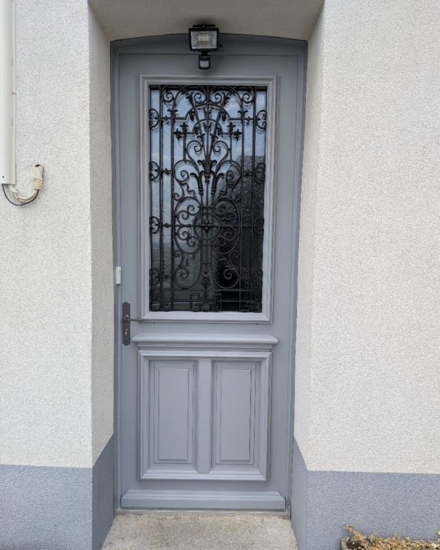 Porte d'entrée en bois sur mesure installée par Menuiserie EGI à Rouen avec finition RAL 7004 et grille restaurée.